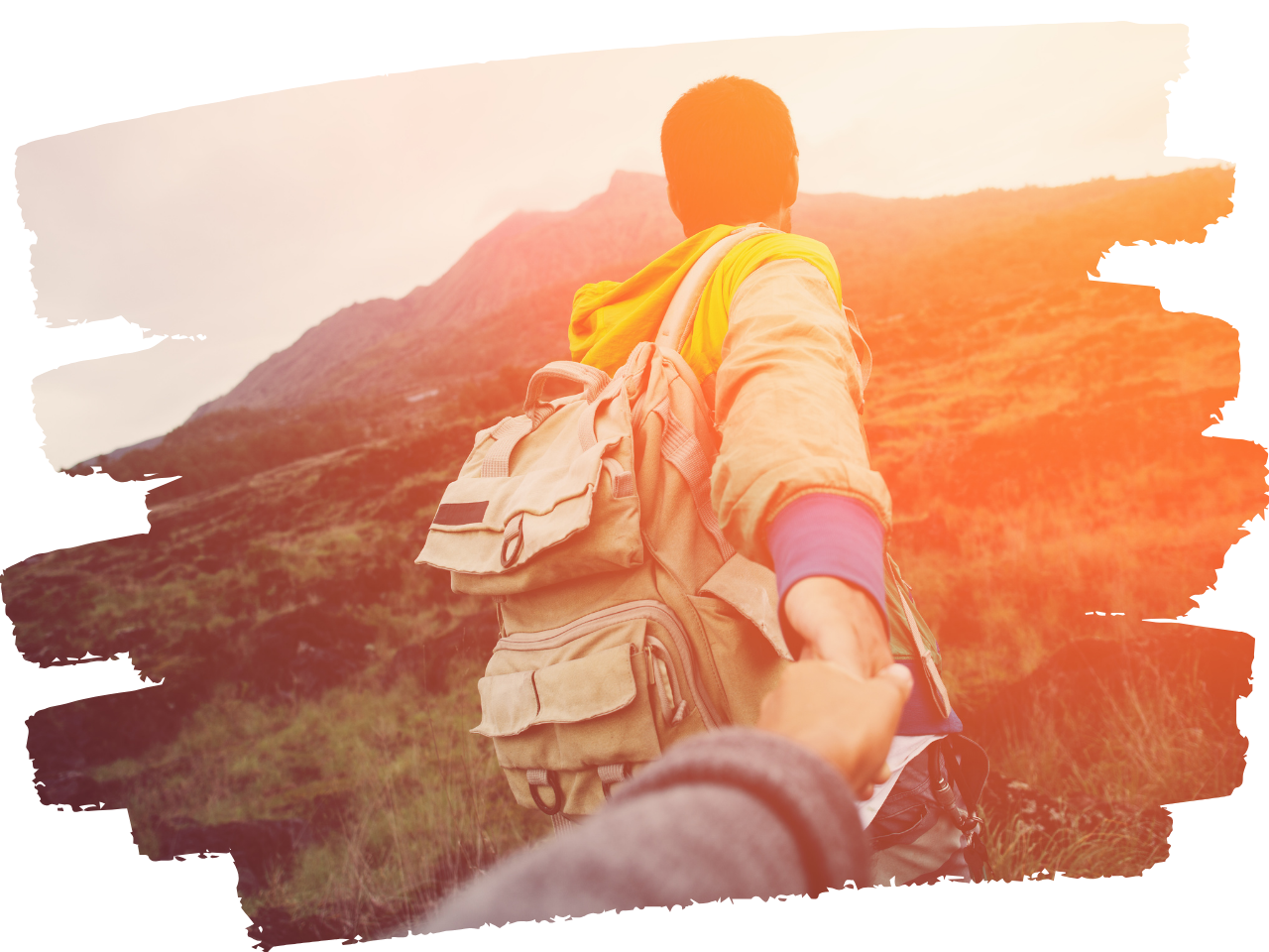 Man hiking up a mountain shown from the back with his arm reached back to grasp the hand of the person behind him.