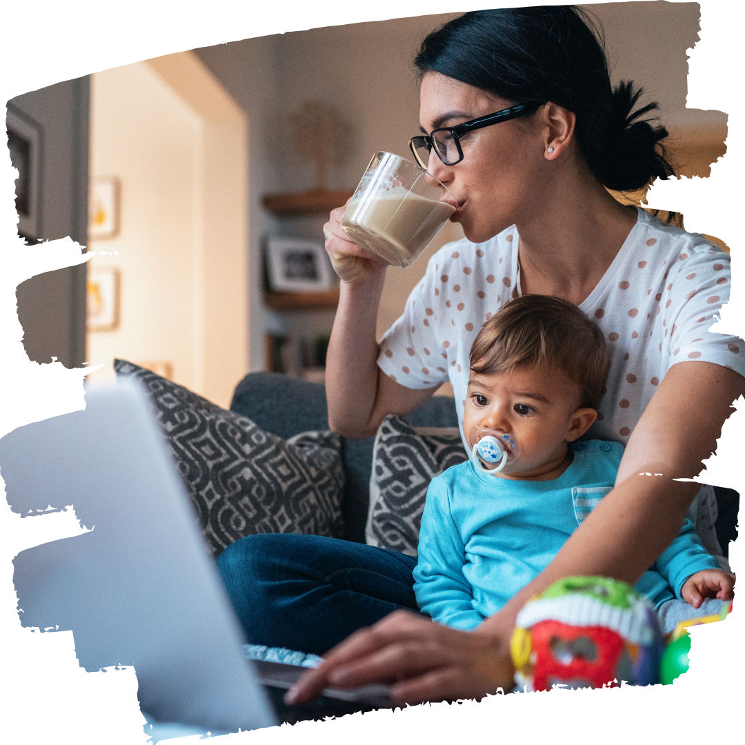 Mom on couch with laptop, coffee, and an infant in her lap