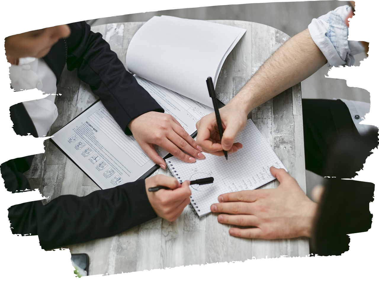 Close up of arms and hands of two people working together with a form and notebook